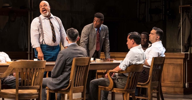 6 men discussing around a table, in the context of a theater play.