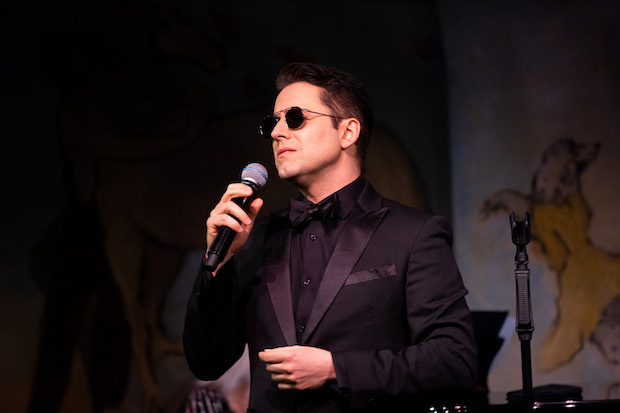 A man in sunglasses holds a microphone. 