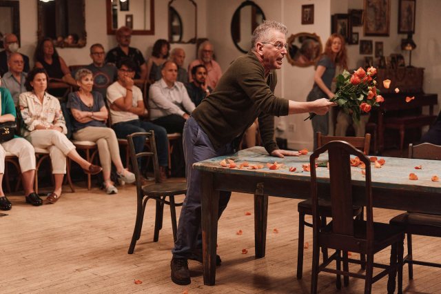 Man holds flowers as he bashes them into the table.