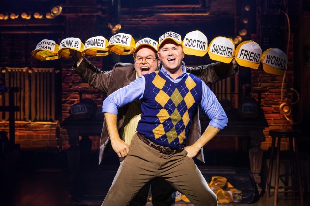 Two men wear baseball caps, with a chorus line of baseball caps (with no wearers) extended out on either side of them. 